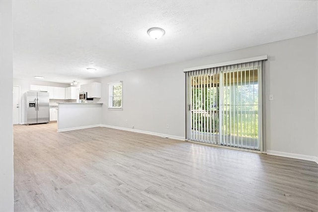 unfurnished living room featuring a textured ceiling and light wood-type flooring