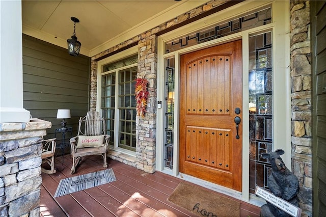 view of exterior entry featuring stone siding and covered porch