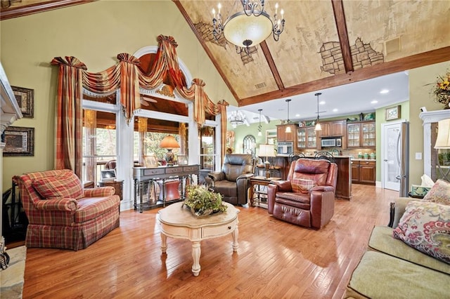 living room with a notable chandelier, light wood-style floors, and high vaulted ceiling