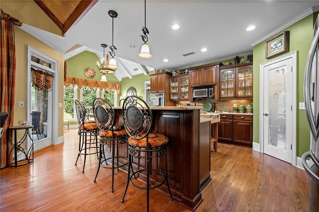 kitchen with visible vents, a breakfast bar, stainless steel appliances, light countertops, and crown molding