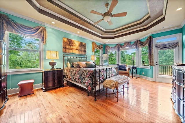 bedroom featuring hardwood / wood-style floors, a tray ceiling, ornamental molding, and access to outside