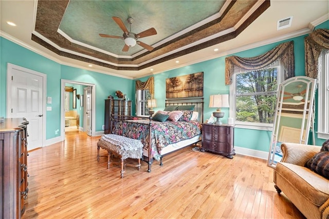 bedroom featuring a tray ceiling, visible vents, ornamental molding, and light wood finished floors