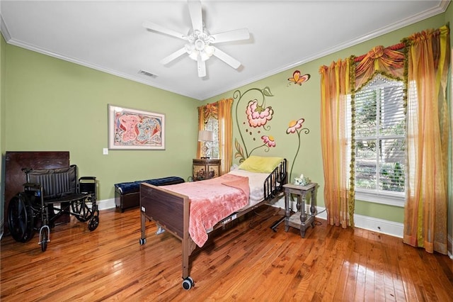 bedroom with hardwood / wood-style floors, visible vents, baseboards, and ornamental molding