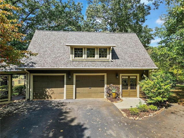 view of front of property with french doors, roof with shingles, and aphalt driveway