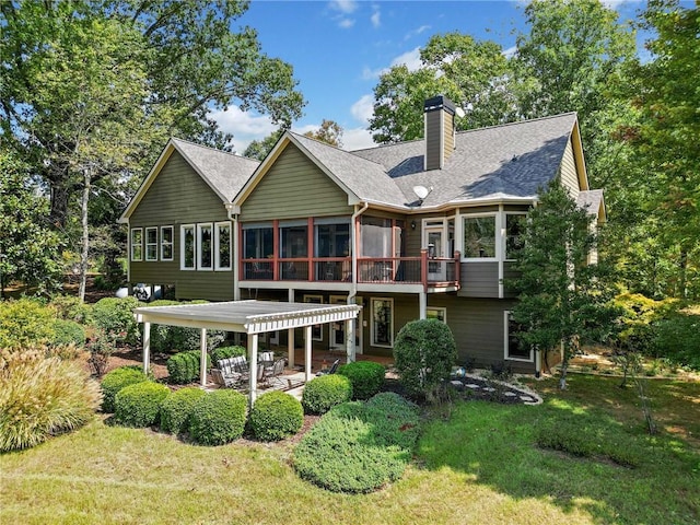 back of house featuring a sunroom, a shingled roof, a chimney, a patio area, and a lawn