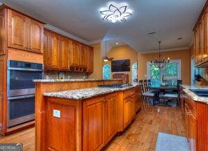 1090 Crown River Pkwy, Mcdonough, GA 30252 - kitchen featuring double oven, brown cabinets, light wood-style floors, and gas stovetop
