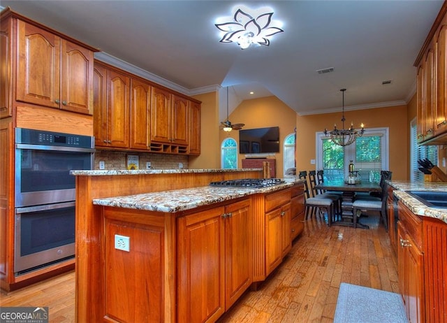 1090 Crown River Pkwy, Mcdonough, GA 30252 - kitchen with stainless steel appliances, brown cabinetry, light stone countertops, a chandelier, and crown molding
