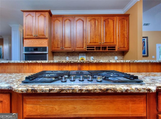 1090 Crown River Pkwy, Mcdonough, GA 30252 - kitchen featuring stainless steel appliances, light stone counters, backsplash, brown cabinetry, and crown molding