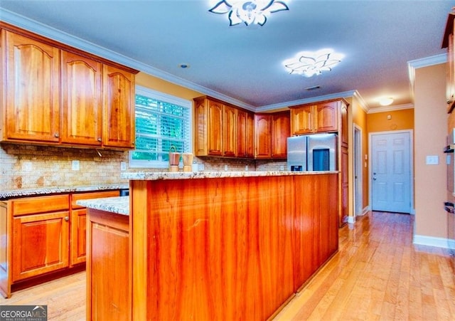 1090 Crown River Pkwy, Mcdonough, GA 30252 - kitchen featuring stainless steel fridge, light wood-style flooring, light stone counters, decorative backsplash, and crown molding