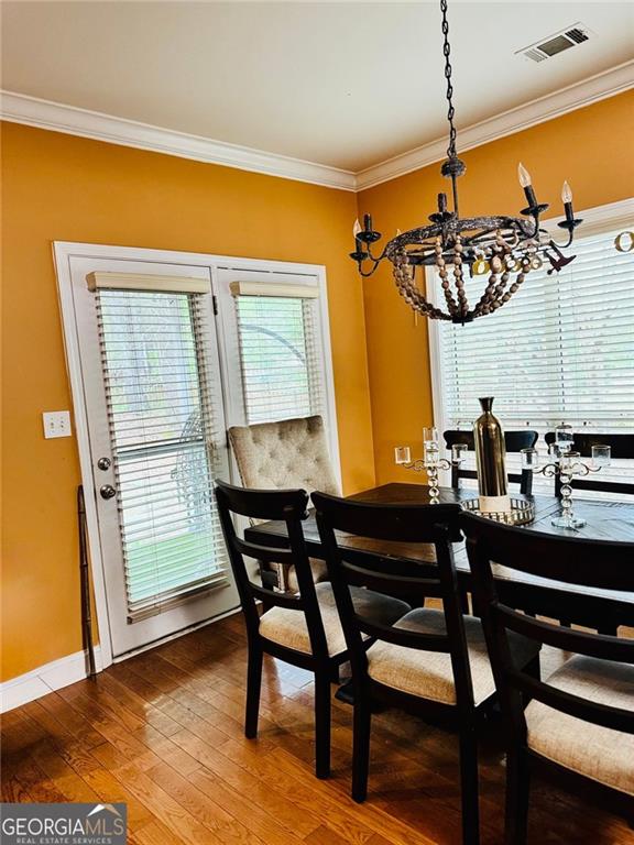 1090 Crown River Pkwy, Mcdonough, GA 30252 - dining space with a chandelier, ornamental molding, hardwood / wood-style flooring, and baseboards
