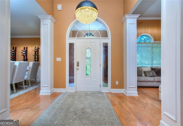 1090 Crown River Pkwy, Mcdonough, GA 30252 - entrance foyer featuring ornate columns, light wood finished floors, a chandelier, a towering ceiling, and ornamental molding
