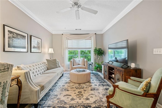 living area featuring ornamental molding, visible vents, a textured ceiling, and a ceiling fan