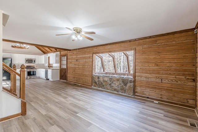 unfurnished living room featuring ceiling fan, light hardwood / wood-style floors, lofted ceiling with beams, and wood walls