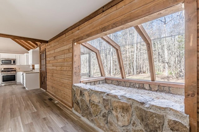 sunroom featuring sink and lofted ceiling with beams