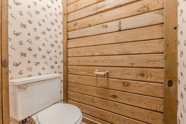 bathroom with wood walls and toilet