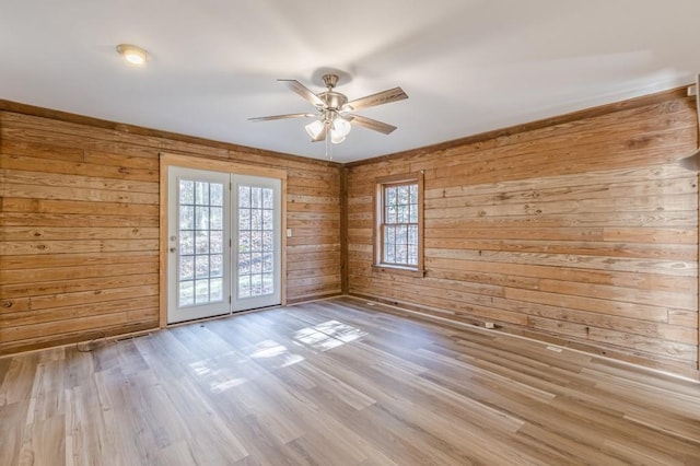 spare room featuring wooden walls, ceiling fan, and light hardwood / wood-style flooring