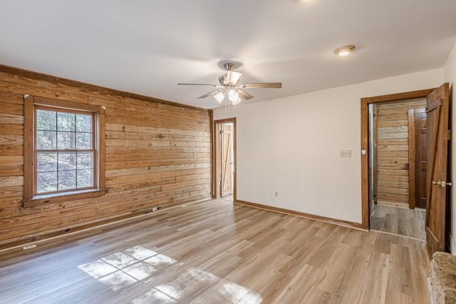 spare room featuring wood walls, ceiling fan, and light hardwood / wood-style flooring