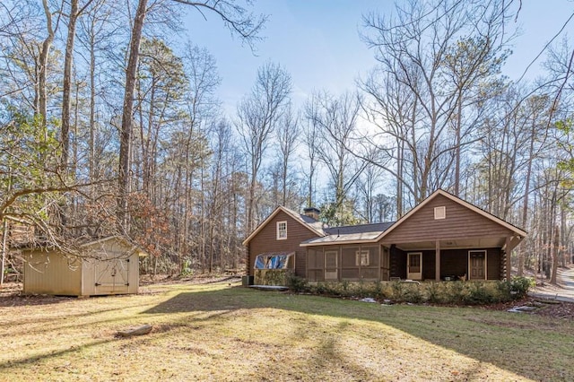 rear view of house with a yard, a sunroom, and a shed