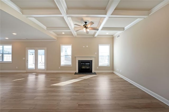 unfurnished living room featuring wood-type flooring, ornamental molding, ceiling fan, beam ceiling, and coffered ceiling