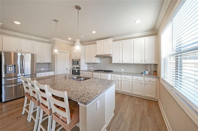 kitchen with appliances with stainless steel finishes, a kitchen breakfast bar, pendant lighting, white cabinets, and sink