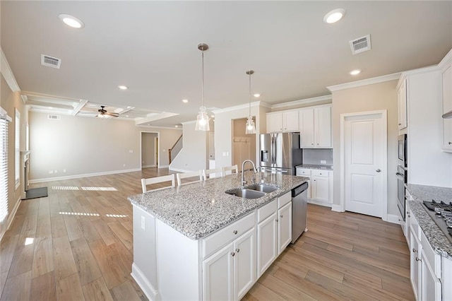 kitchen with white cabinetry, stainless steel appliances, an island with sink, sink, and ceiling fan