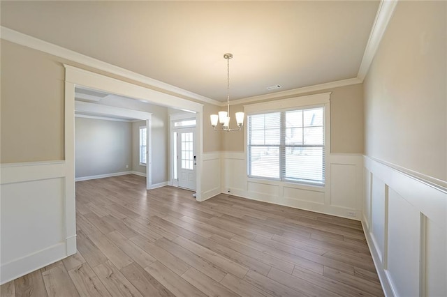 unfurnished dining area featuring ornamental molding, a chandelier, and light hardwood / wood-style flooring