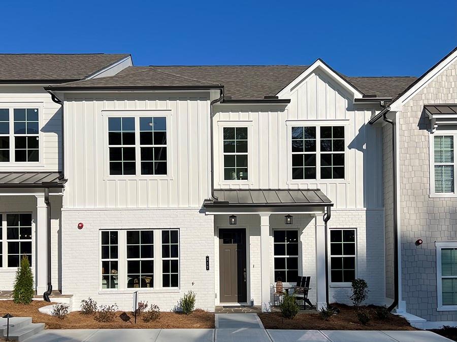 modern inspired farmhouse featuring a standing seam roof, brick siding, board and batten siding, and metal roof