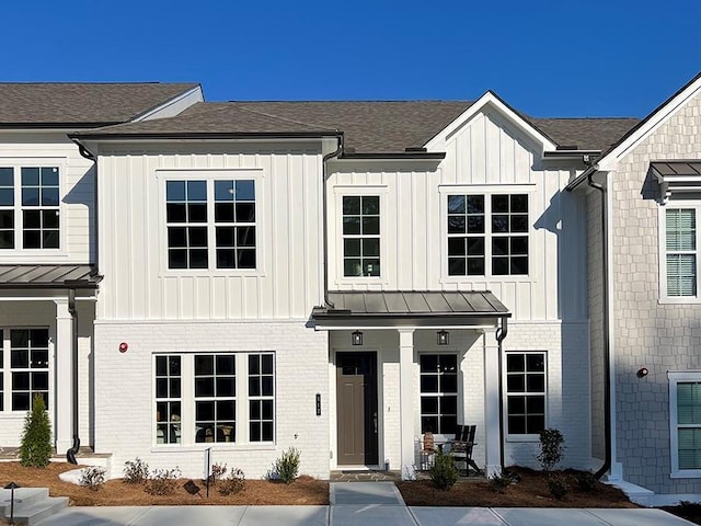 modern inspired farmhouse featuring a standing seam roof, brick siding, board and batten siding, and metal roof