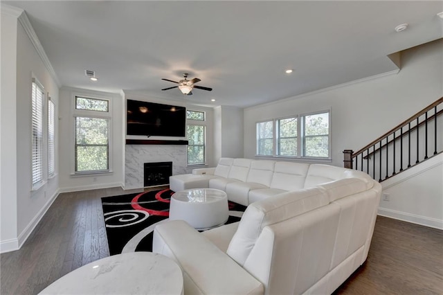 living room featuring a fireplace, dark hardwood / wood-style flooring, ceiling fan, and crown molding