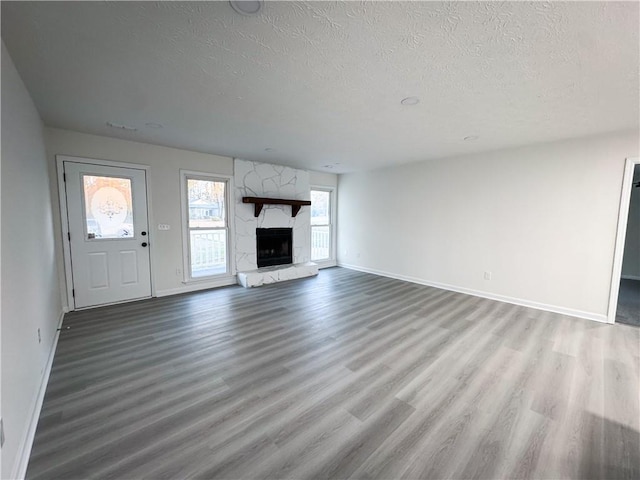 unfurnished living room with a fireplace, wood-type flooring, and a textured ceiling