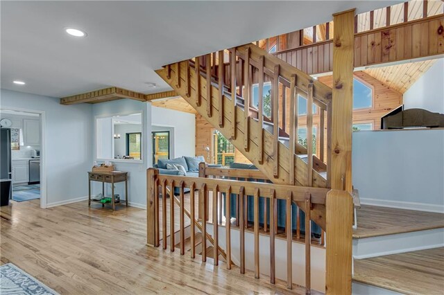 living room with ceiling fan, wooden walls, light hardwood / wood-style floors, and high vaulted ceiling