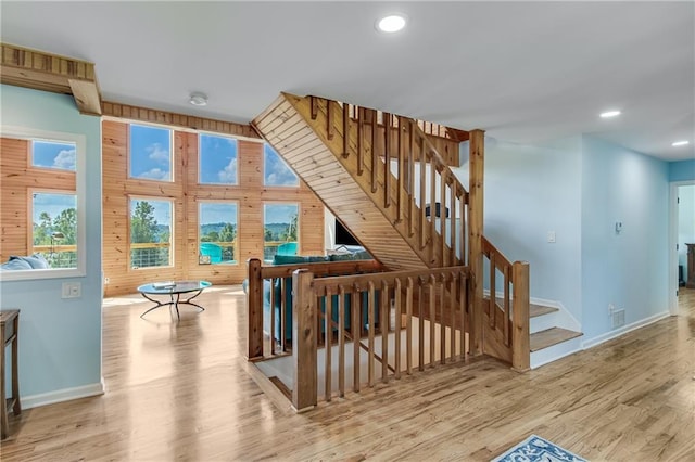 staircase featuring recessed lighting, baseboards, wooden walls, and wood finished floors