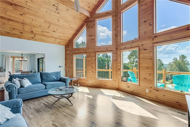 living room with wood ceiling, wooden walls, a chandelier, high vaulted ceiling, and light wood-type flooring