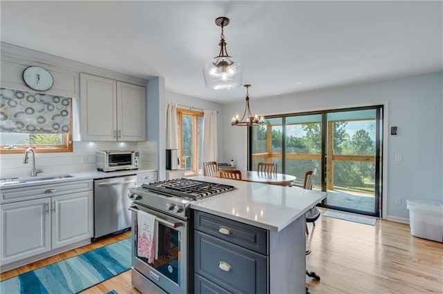 kitchen featuring a notable chandelier, stainless steel appliances, light countertops, and a sink