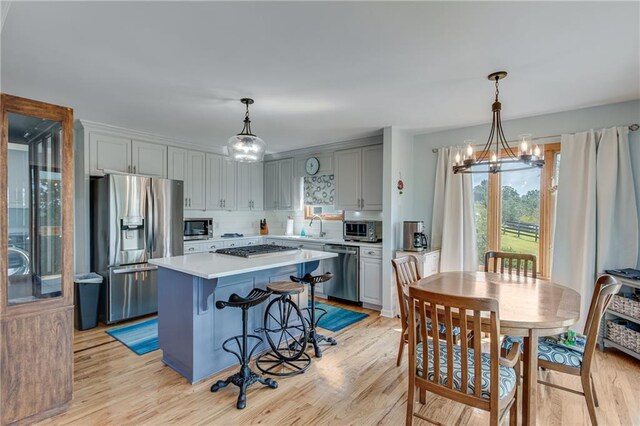 kitchen featuring light hardwood / wood-style flooring, a center island, a notable chandelier, and appliances with stainless steel finishes