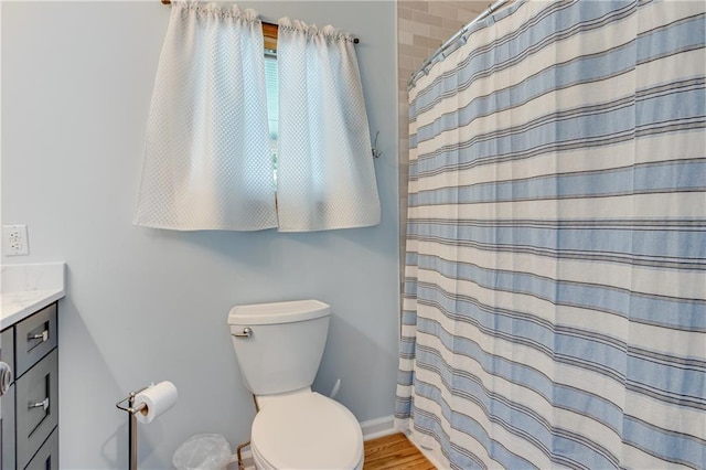 bathroom with toilet, wood finished floors, a shower with shower curtain, baseboards, and vanity