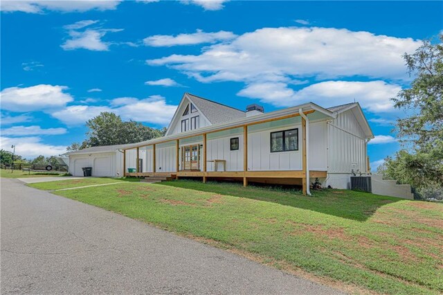 view of front of property with a garage, a front lawn, covered porch, and central air condition unit