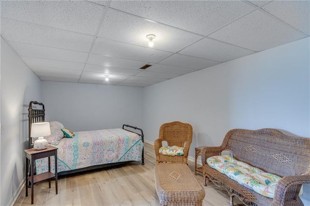 bedroom featuring light wood-style flooring, a paneled ceiling, visible vents, and baseboards