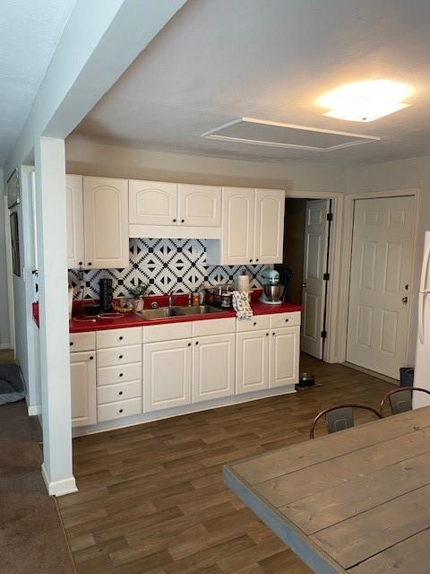 kitchen with white cabinets, dark wood-style floors, backsplash, and a sink
