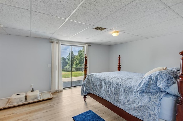 bedroom featuring visible vents, baseboards, wood finished floors, a paneled ceiling, and access to outside