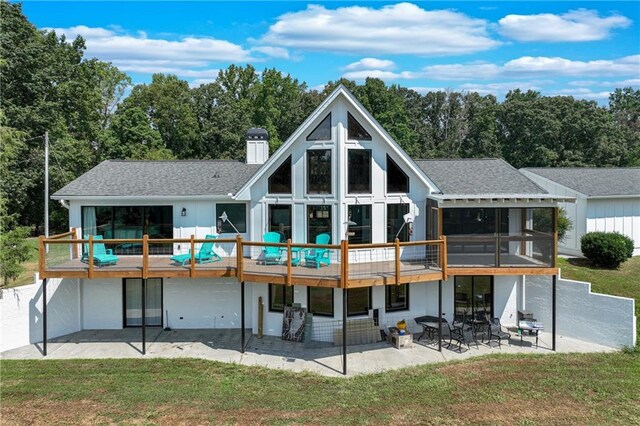 back of property with a sunroom, a patio area, a deck, and a yard