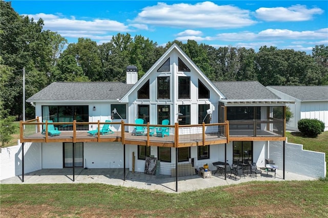 back of property featuring a yard, a patio, a chimney, and a sunroom