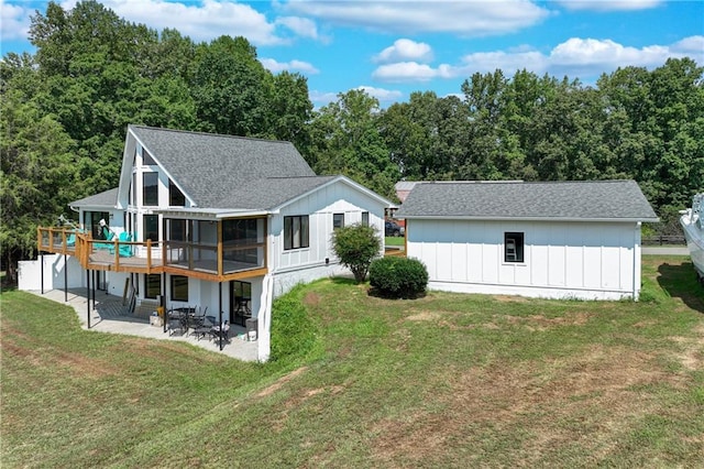 rear view of property featuring a patio, a lawn, and a shingled roof