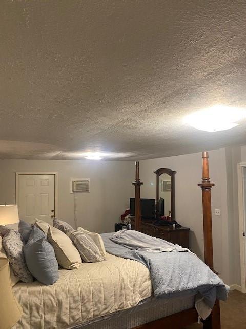 bedroom with a textured ceiling and a wall unit AC