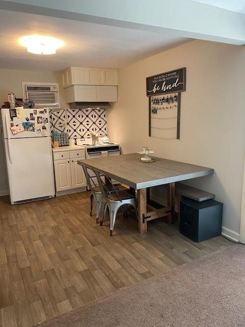 dining area featuring hardwood / wood-style floors and a wall unit AC