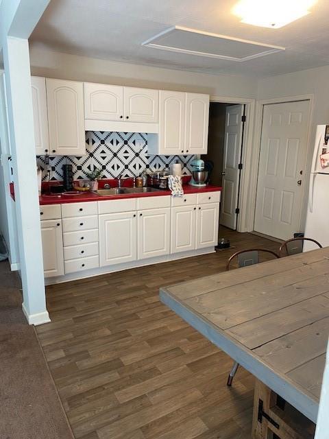 kitchen with white cabinetry, dark wood-style flooring, freestanding refrigerator, and a sink
