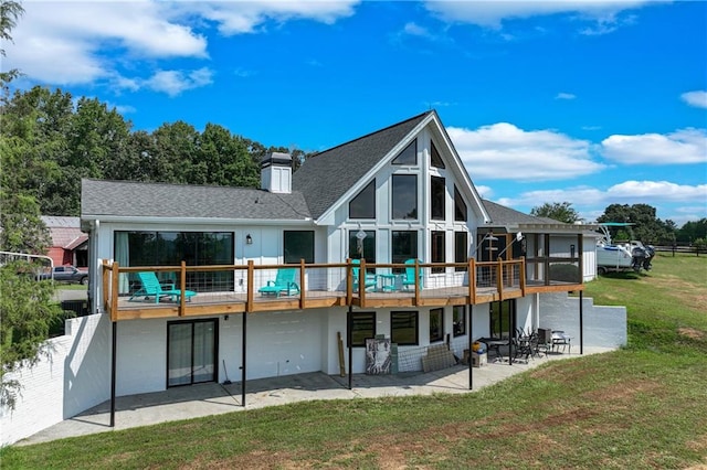 rear view of property featuring a patio, a lawn, a deck, and a chimney