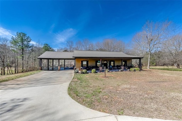 view of front of property featuring an attached carport, driveway, and metal roof