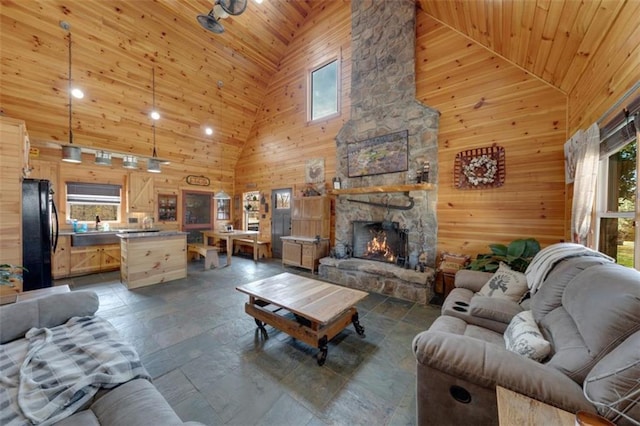 living area featuring high vaulted ceiling, a fireplace, wood walls, and wooden ceiling