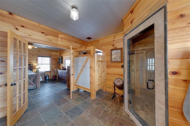 full bathroom featuring french doors, a stall shower, and wood walls